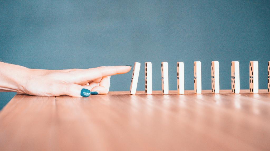 hand touching a piece of domino in a row of many pieces